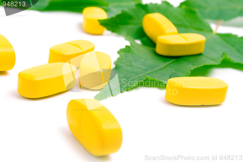 Image of yellow vitamin pills over green leave