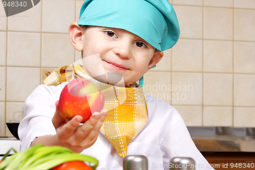 Image of Little cook boy giving red apple