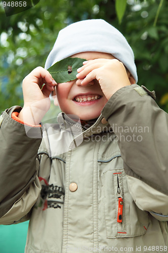 Image of Smiling boy looking through leaf