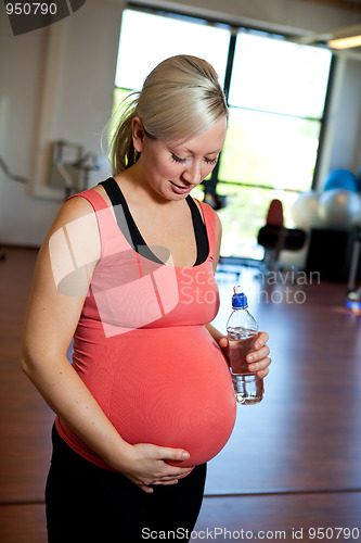 Image of Pregnant woman relaxing while holding water bottle.