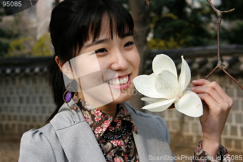 Image of Pretty Korean woman holding a flower in spring