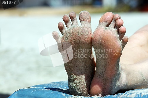 Image of Feet of woman lying on the beach