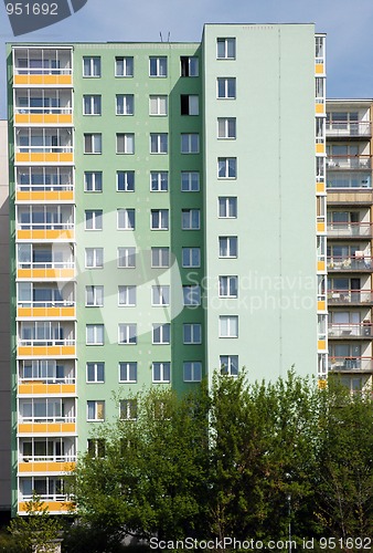 Image of Green prefab house with many windows and trees in front of it
