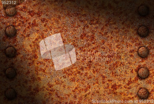 Image of Rusted metal surface with rivets diagonally lit