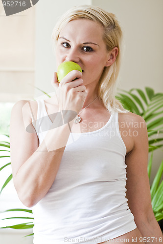 Image of Young beautiful woman eating green apple