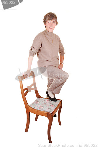 Image of Lady standing on chair.
