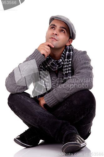 Image of Portrait of a young man sitting on the floor, thinking and looking up