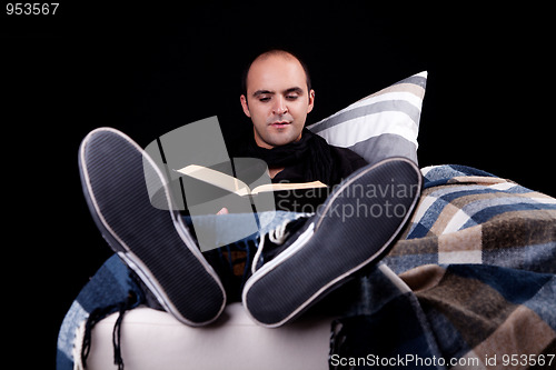 Image of man lying on the sofa reading a book