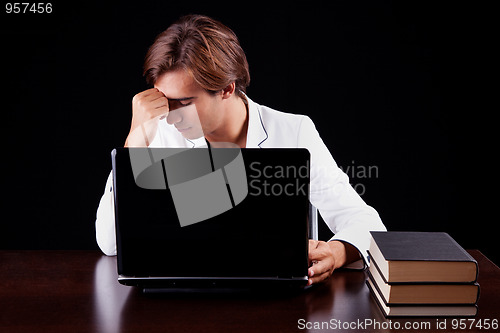 Image of Tired young businessman on the computer 