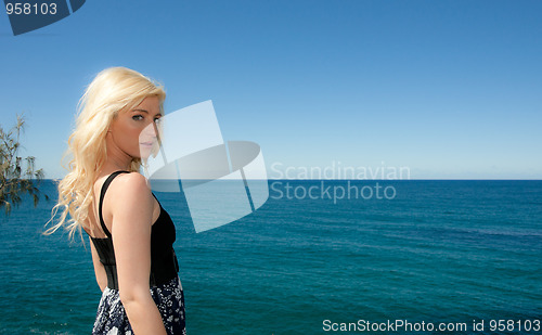 Image of young woman looks over blue ocean