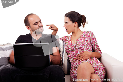 Image of couple sitting on the couch, he playing computer and she argues with him