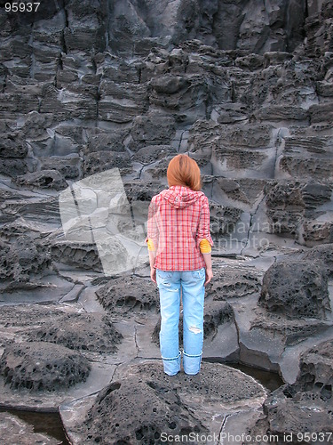 Image of Woman standing on volcanic rock