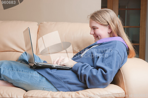 Image of teenager using laptop on sofa
