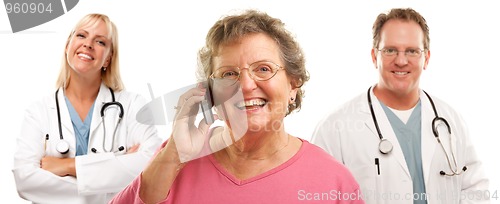 Image of Happy Senior Woman Using Cell Phone and Doctors Behind