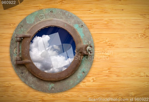 Image of Antique Porthole on Bamboo Wall with View of Blue Sky and Clouds