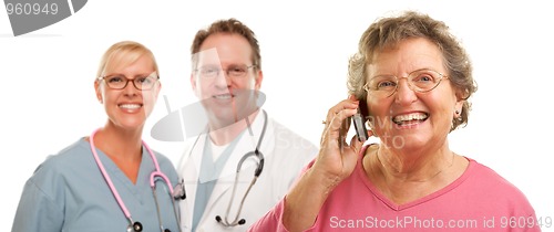 Image of Happy Senior Woman Using Cell Phone and Doctors Behind