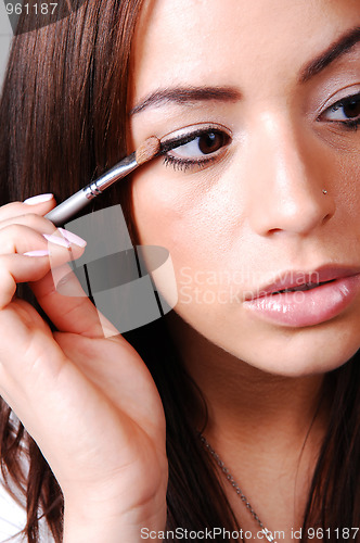 Image of Young woman putting makeup.