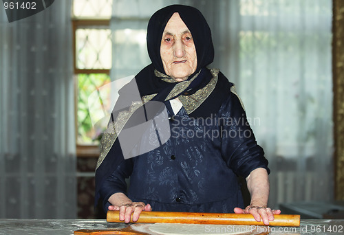 Image of Elderly woman rolling out dough