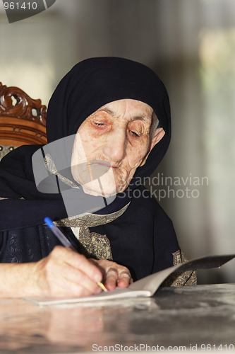 Image of Elderly woman writing at table