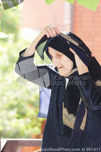 Image of Elderly woman adjusting headscarf