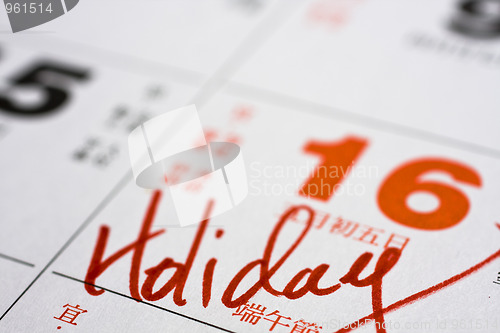 Image of Hand writing holiday on calendar