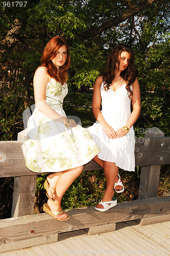 Image of Two sisters sitting on bridge.