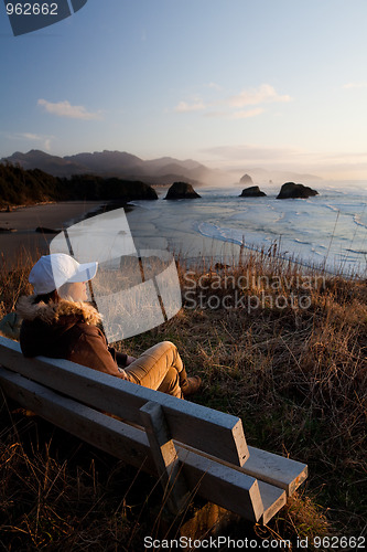 Image of woman on bench overlooking beach