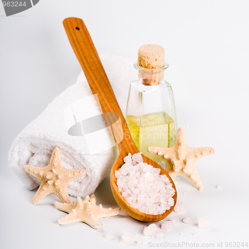 Image of sea salt on wooden spoon, towel, oil and stars