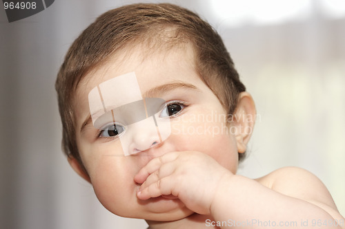 Image of Cute baby with hand at mouth