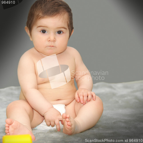 Image of Serene baby sitting on gray carpet