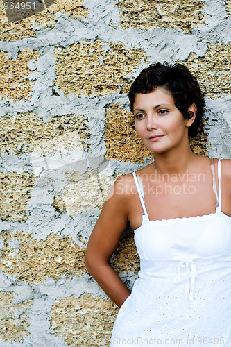 Image of woman in white dress near a brick wall