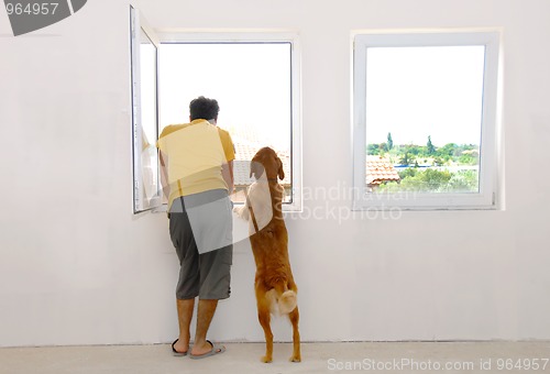 Image of Man and dog looking through window