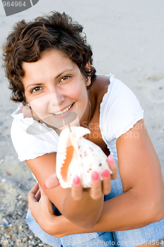 Image of  woman on seacoast with a cockleshell in hands 