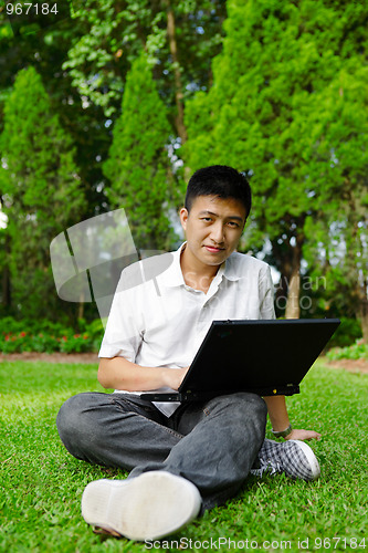 Image of asian man using computer outdoor