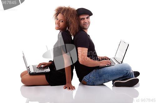 Image of Couple back to back, sitting on the floor, with computers