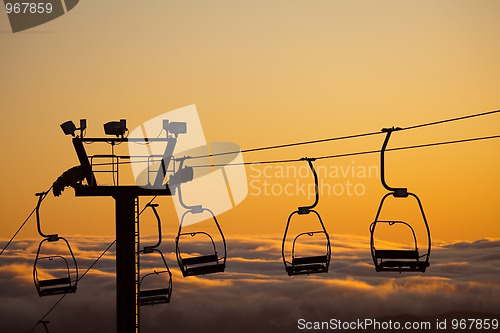 Image of ski lift over clouds in sunset