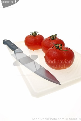 Image of Cutting white plastic board with a knife and tomato