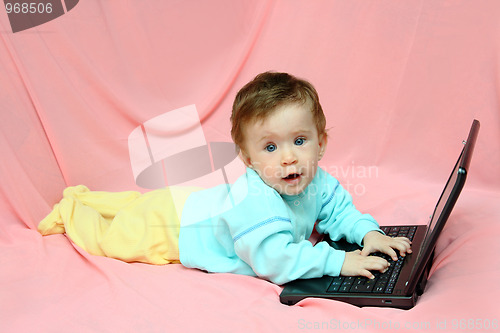 Image of baby lying with laptop