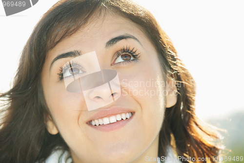 Image of Young brunette in sunlight looking up