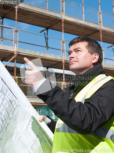 Image of Builder points up at construction site