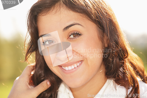 Image of Young smiling brunette touching hair
