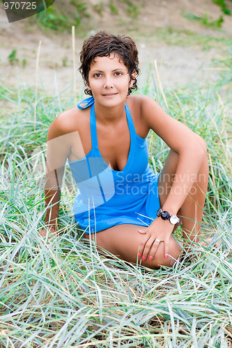 Image of woman in blue sitting in a grass