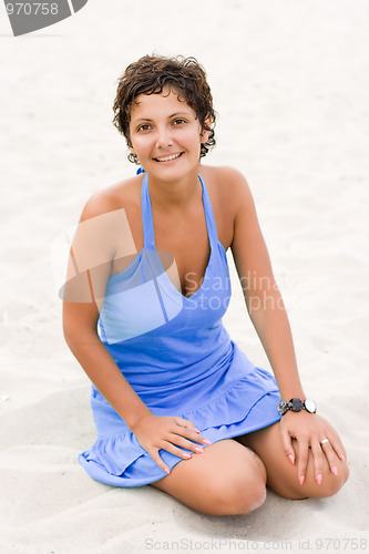 Image of woman in blue sitting in a sand