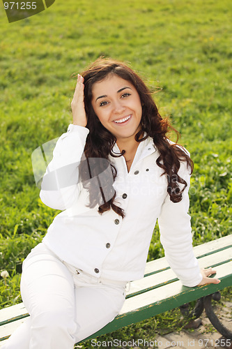 Image of Young smiling brunette sitting on bench