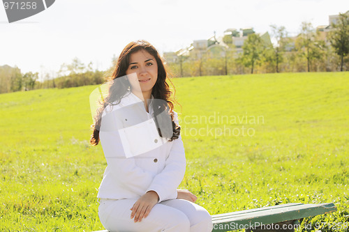 Image of Young brunette sitting on bench