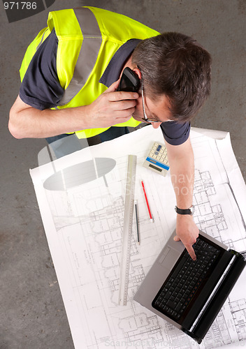 Image of Builder phones about construction blueprint