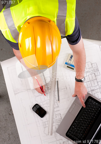 Image of Builder inspects construction plans.