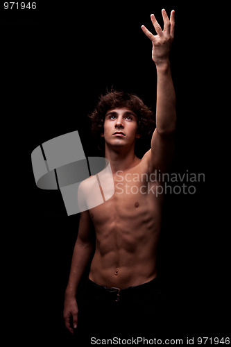 Image of young man in topless looking up to the light and raising arm - sign of faith 