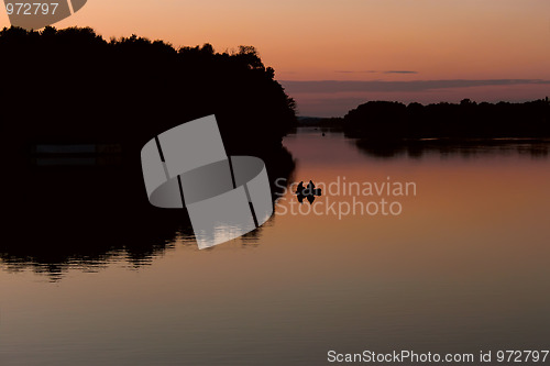 Image of Fishermen on a boat floating on the lake after sunset