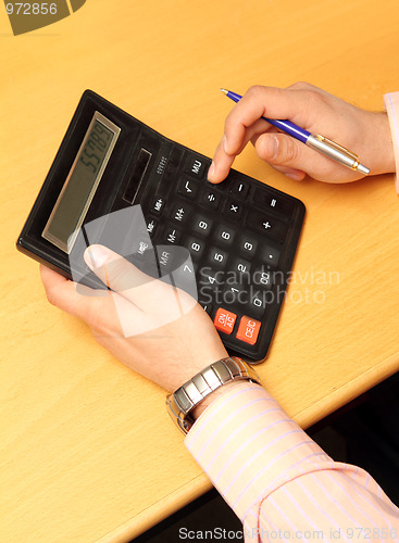 Image of businessman counts money on calculator